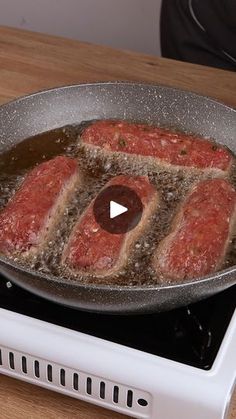 raw meat being cooked in a pan on top of an electric stove with the lid open