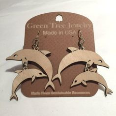 three wooden dolphins are hanging from the back of a pair of dangle earrings in front of a white background