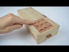 a hand is pressing the numbers on a wooden box