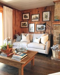 a living room filled with furniture next to a fire place in a wooden paneled wall