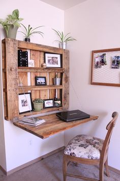 a wooden desk topped with a laptop computer next to a wall mounted book shelf filled with pictures