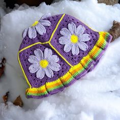 a crocheted hat with flowers on it laying in the snow