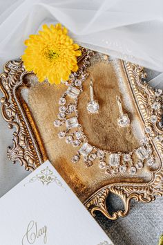 a yellow flower sitting on top of a table next to a card and some jewelry