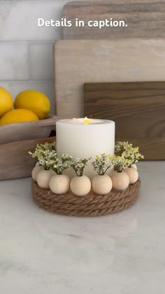 a white candle sitting on top of a table next to lemons and other fruit