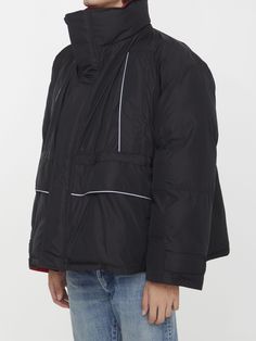 Balenciaga Wrap parka in black matte nylon with contrast red lining. It features high stand-up collar, foldable hood without drawstring, concealed zipped closure with snap buttons, four zipped slash pockets at front, drawstring at waistline, adjustable hook and loop straps at cuffs and Balenciaga logo at back collar. Oversized fit. The model is 190cm tall and wears size 01.Size nationality: US Product number: 1176339 Product code: 751715TNO191000 Composition: 100% polyamide Black Nylon Puffer Jacket With Drawstring Hood, Black Sporty Puffer Parka, Urban Black Windbreaker With Padded Collar, Black Parka With Padded Collar For Streetwear, Black Sporty Puffer Jacket With Detachable Hood, Black Hooded Windbreaker With Padded Collar, Black Nylon Windbreaker With Padded Collar, Black Windbreaker With Padded Collar For Cold Weather, Sporty Black Parka With Double-lined Hood