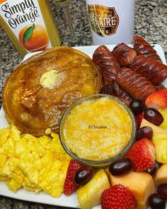 a breakfast plate with eggs, fruit, sausages, pancakes and other food items