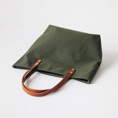 The Green Canvas tote is a canvas and leather tote handmade in the KMM & Co. studio in Atlanta. Each one is meticulously crafted from heavyweight canvas and gorgeous full-grain leather. Green Canvas is a type of cotton canvas known as duck cloth. It's one of the most durable types of cloth, and it's structured enough to stand up on its own. The Green Canvas tote comes standard with Tan handles. Green Canvas Bag With Double Handle, Green Double Handle Canvas Bag, Green Duck Canvas Bag For Daily Use, Modern Everyday Canvas Bag With Canvas Lining, Green Duck Canvas Bag With Canvas Lining, Large Canvas Bag With Leather Handles, Green Duck Canvas Tote Bag, Canvas Tote Bag With Top Carry Handle, Daily Use Canvas Bag With Leather Handles