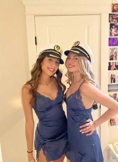 two beautiful young women dressed in sailor hats posing for a photo while standing next to each other