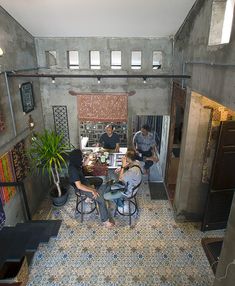 two men sitting at a table in a room with tile flooring and large windows