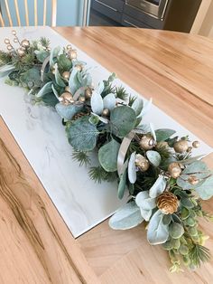 the table is decorated with greenery, pine cones and gold ornaments on it's edge