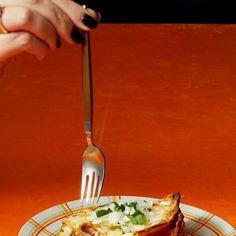 a person is holding a fork and knife over a piece of food on a plate