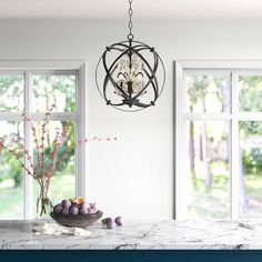 a chandelier hangs from the ceiling over a marble countertop in front of two windows