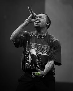 a man with his hands in the air while holding a bottle and wearing a necklace