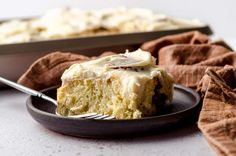 a piece of cake on a plate with a fork next to it and a baking pan in the background