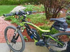 a green and black bike parked on the side of a road next to some bushes