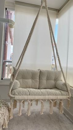 a white couch hanging from a rope in front of a window