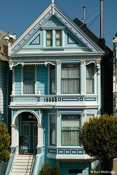 a blue house with white trim on the front and stairs leading up to it's second story