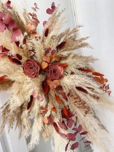 an arrangement of dried flowers and leaves on a door