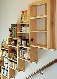 a wall mounted spice rack on the side of a wall next to a stair case