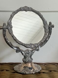 an ornate silver mirror sitting on top of a table