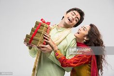 a man holding a gift box and smiling at the camera while standing next to a woman