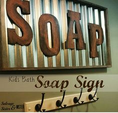 a metal sign that says soap hanging on the wall next to some hooks and a coat rack