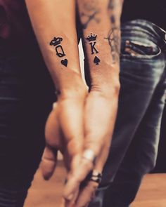 two people holding hands with tattoos on them