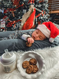 a baby in a santa hat is eating cookies