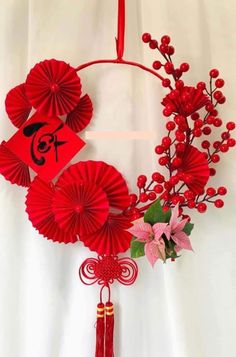 a red decoration hanging from the side of a white wall with flowers and decorations on it