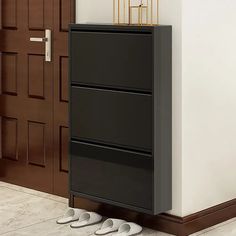 two pairs of shoes sitting on the floor in front of a black filing cabinet and door