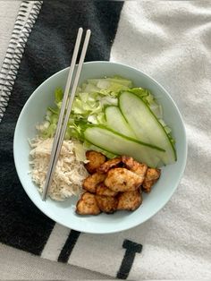 a bowl filled with rice, meat and veggies next to chopsticks