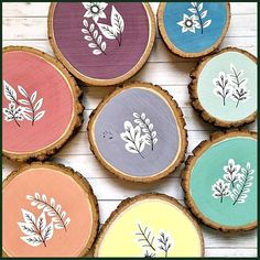 six painted wood slices with flowers and leaves on each one, all in different colors