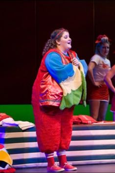 a group of women standing on top of a stage next to each other wearing costumes