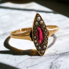 Introducing our exquisite Victorian Era ring, a timeless masterpiece that captivates with its elegance and grace. Crafted from 14K rose gold, this ring features a stunning central marquise-shaped pink tourmaline, radiating with a deep blush hue reminiscent of romance and refinement.  Surrounding the tourmaline are lustrous pearls, each one carefully selected to complement the gemstone's beauty and add a touch of sophistication.  With intricate Victorian-era detailing and craftsmanship, this ring Luxury Pink Marquise Ring, Pink Marquise Ruby Ring For Formal Occasions, Formal Marquise Pink Ruby Ring, Formal Pink Marquise Ruby Ring, Fine Jewelry Pink Marquise Ruby Ring, Pink Marquise Ruby Ring Fine Jewelry, Luxury Marquise Ruby Ring For Wedding, Marquise Ruby Ring In 14k Gold, Pink Marquise Ring For Formal Occasions