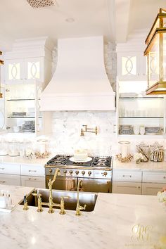 a kitchen with white marble counter tops and gold faucets on the stove top