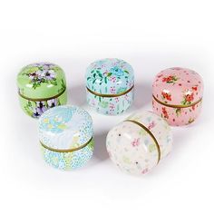 four small round boxes with floral designs on them