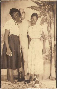 an old black and white photo of three people posing for a picture in front of a palm tree