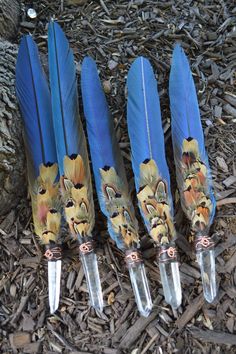 three blue feathers with animals on them are sitting next to some knifes and knives