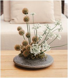 a vase filled with white flowers sitting on top of a wooden table next to a couch