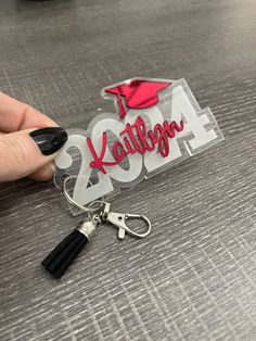 a person holding a keychain with a graduation cap on it