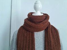 a brown knitted scarf sitting on top of a mannequin