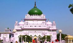 people are walking around in front of a white building with a green dome on top