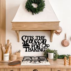 a stove top oven sitting inside of a kitchen next to a wall mounted sign that says it's the season for baking