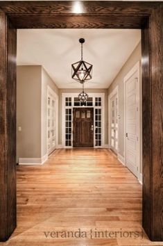 an empty hallway with wood floors and chandelier