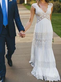 a man and woman holding hands while walking down a sidewalk