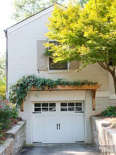 a white garage with plants growing on the roof