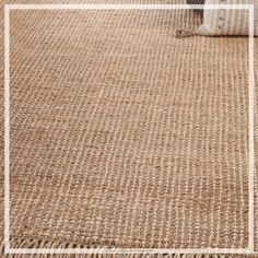 a brown rug with a white square frame on the top and bottom, in front of a couch