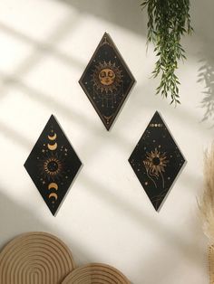 three sun and moon wall hangings on the wall next to a potted plant