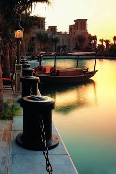 an outdoor dining area with tables and chairs next to a body of water at sunset