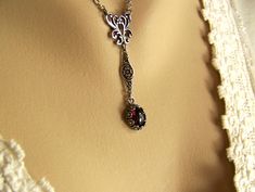 "A genuine red garnet is set in an antique silver floral bezel. The deep red natural stone is hung from a flower accented connector to a scrolling silver pendant. The silver plated chain is closed with an open floral box chain.  The stone is 10x8mm (approximately 1/2\" x 1/4\"). The JBB silver flower bezel has tiny flowers surrounding the natural deep red stone. The necklace is approximately 18\" long, but can be customized by request. The scroll pendant, flower connector and set stone are approximately 2\" in overall length.  This is a lovely gift for a January birthday or just a lovely compliment to any outfit.  To see more of my designs click on this link: www.etsy.com/shop/createdinthewoods I am not responsible for any customs or duty fees on international orders. That is solely the re Victorian Drop Jewelry Gift, Red Garnet Necklace, Acorn Necklace, January Birthday, Garnet Pendant, Garnet Necklace, January Birthstone, Box Clasp, Tiny Flowers